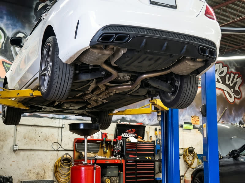 The underside of a car on the lift, exhaust and suspension in view