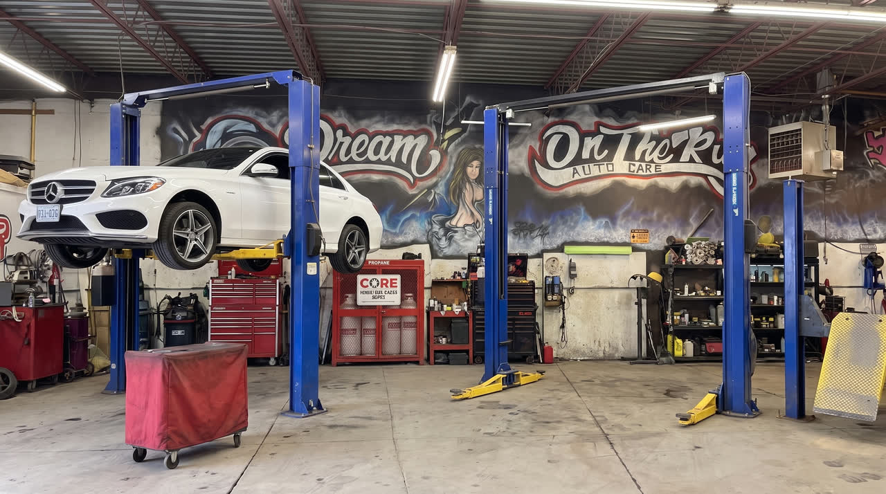 A car on the lift in front of the shop mural